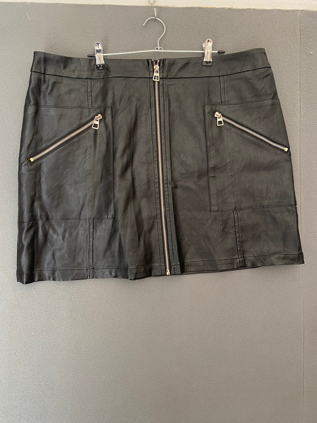 Mini-jupe plissée en simili cuir à grosse boucle
